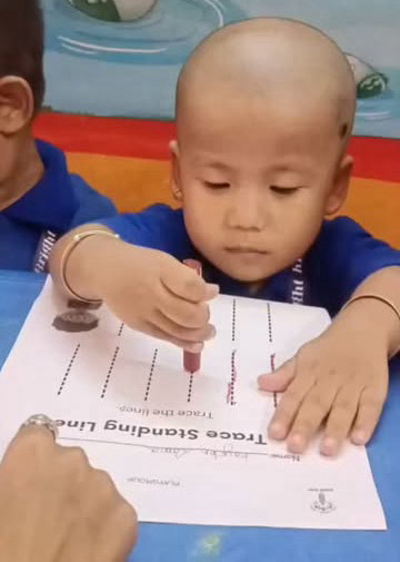 A child tracing standing lines on a worksheet